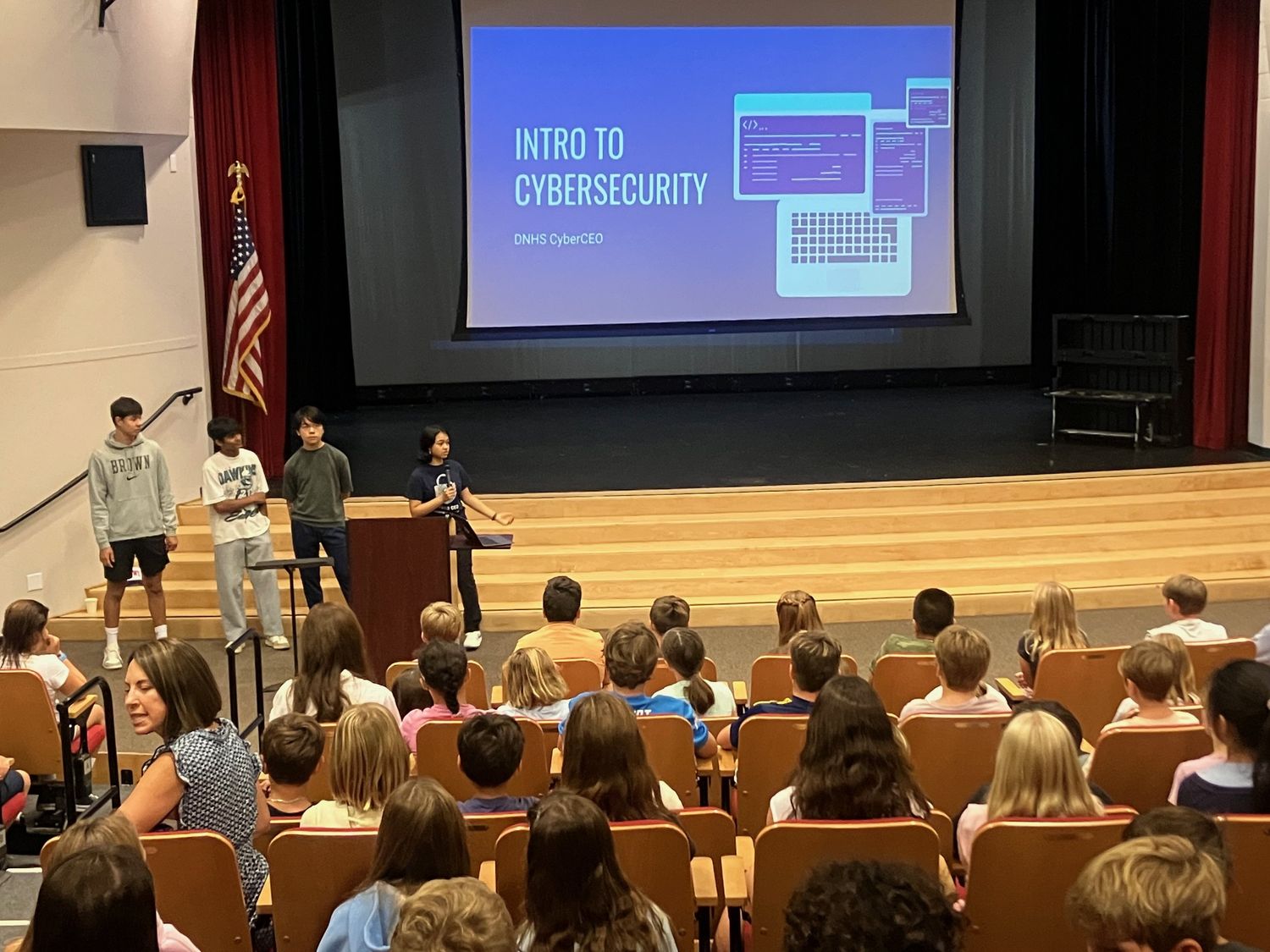 Four CyberCEO members presenting to an elementary school assembly