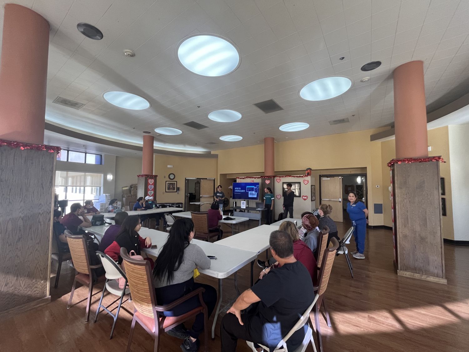 Staff and residents seated at tables during a CyberCEO workshop at a senior residence